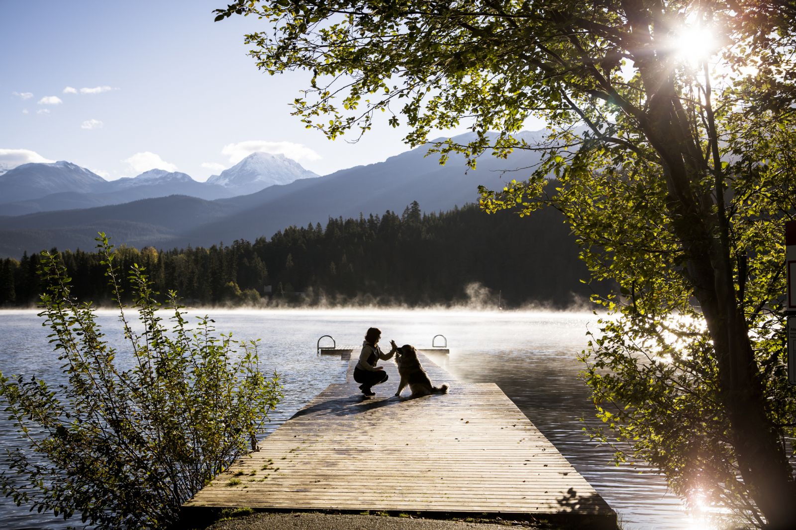 A woman enjoys a lake park with her dog near Whistler
